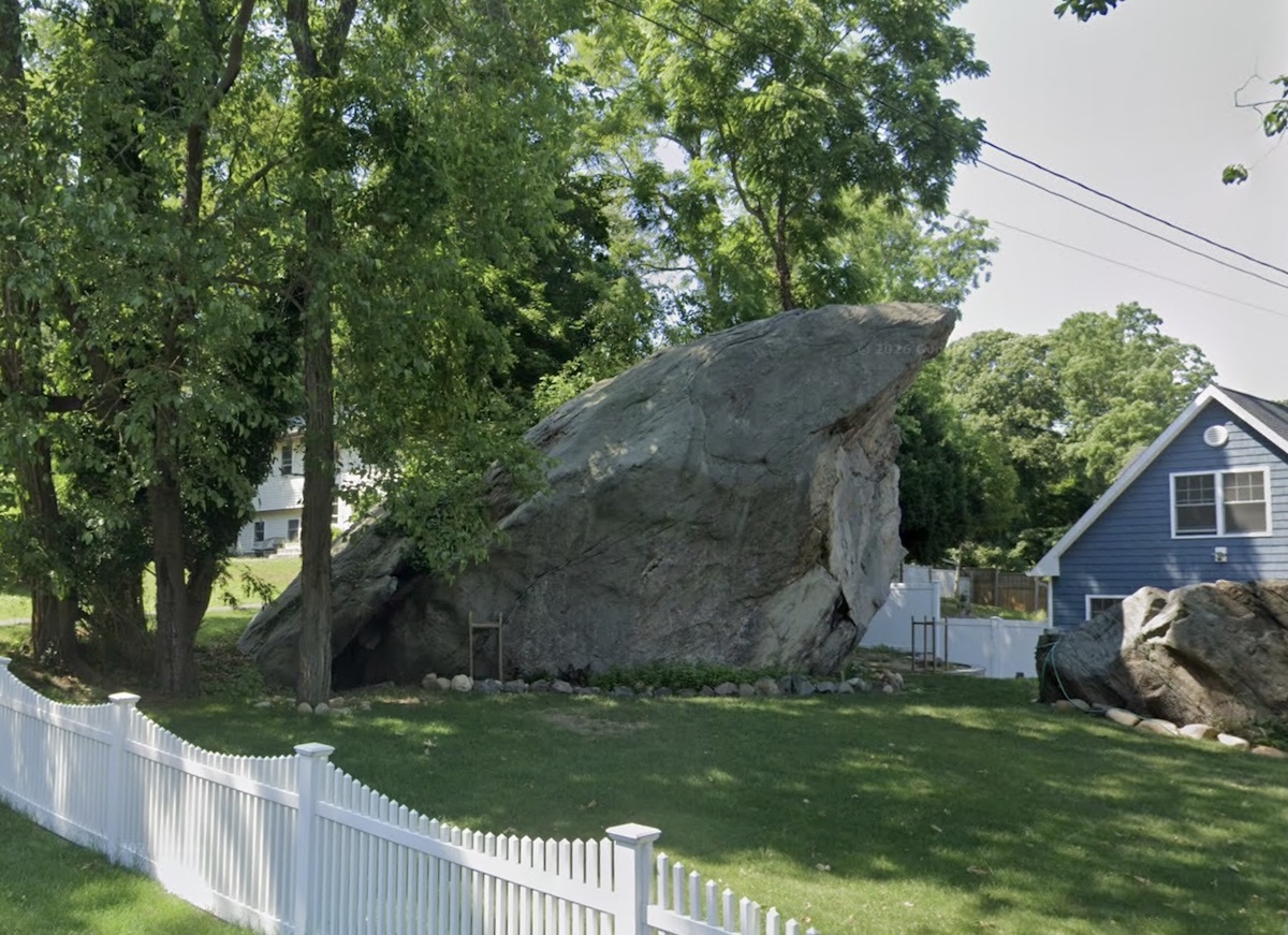 Modern Google Maps view of Indian Rock, a massive glacial boulder on Sam's Path in Rocky Point, Long Island, surrounded by trees and residential homes.